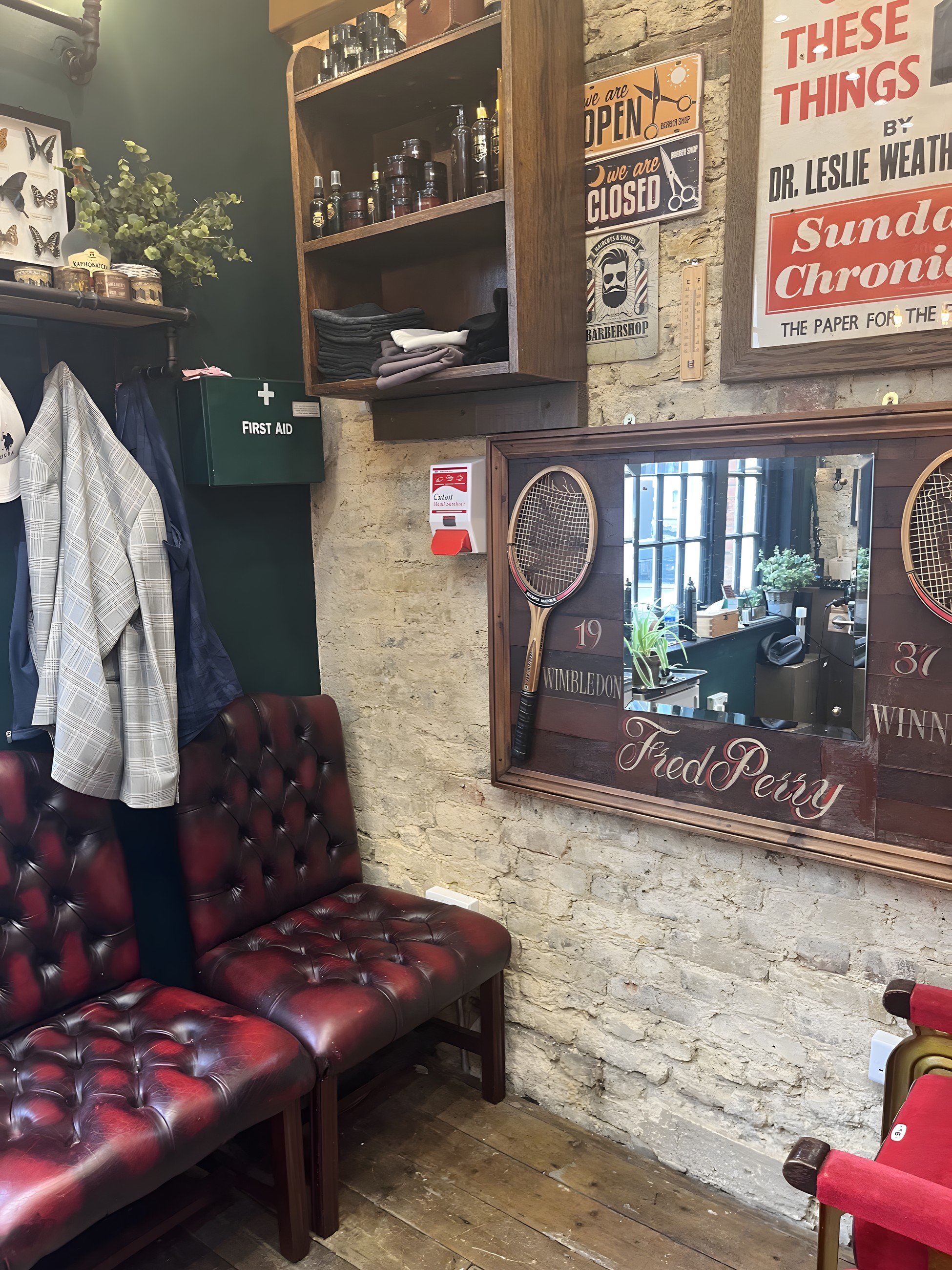 The waiting area with red leather chesterfield seating and a framed Fred Perry mirror